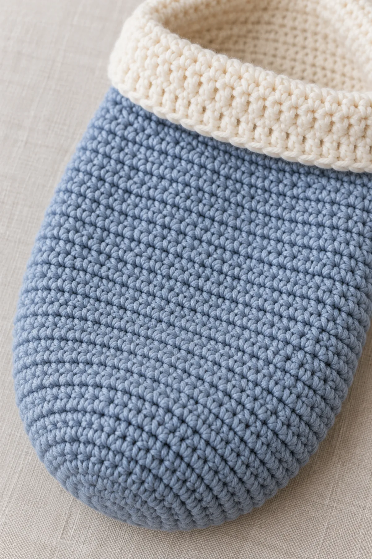 Close-up of even twilight-blue half-double-crochet stitches, flat closed lower seam, and soft ivory folded opening