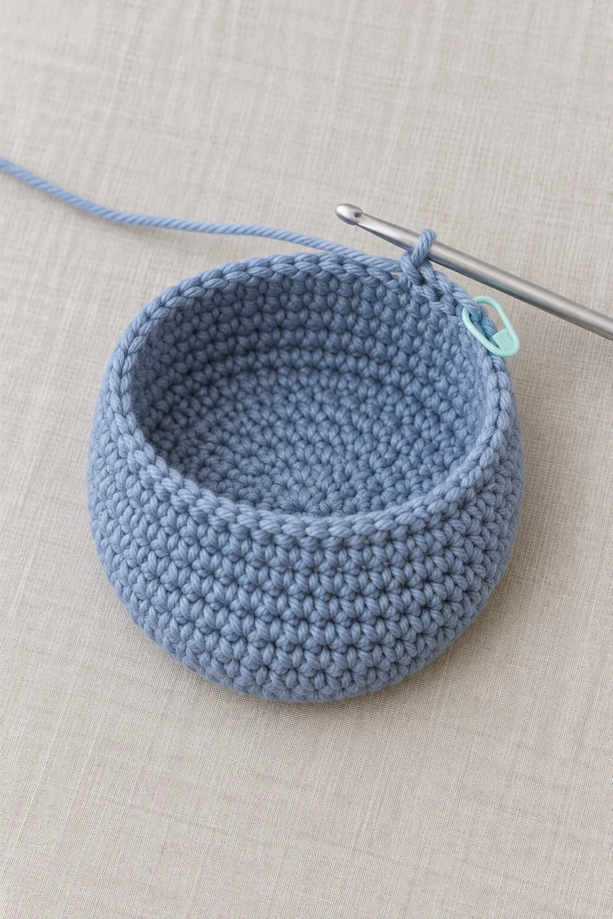Twist-free joined 50-stitch twilight-blue foundation ring and early half-double-crochet rounds with a marker and hook