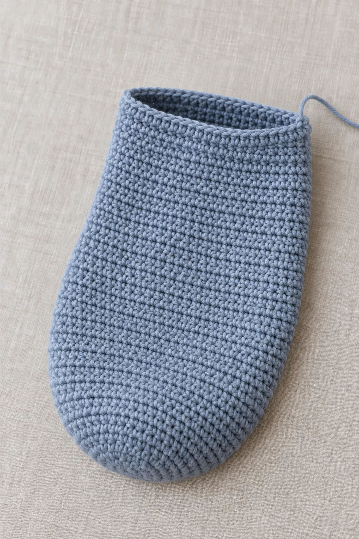 Nearly complete twilight-blue crochet photo cocoon tube before its flat lower closure and ivory upper ribbing