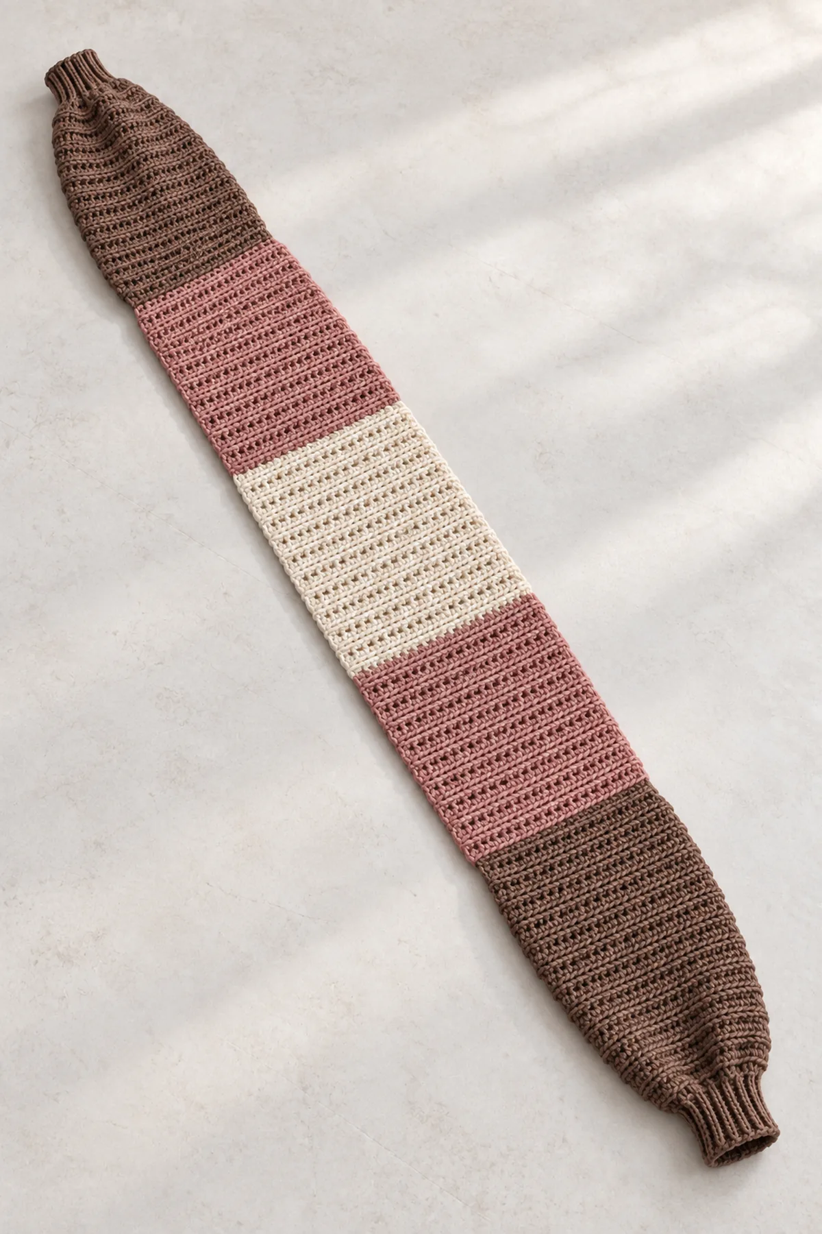 Cocoa, rose and cream ribbed crochet sleeve scarf laid flat with a cuff at each end and an open center.