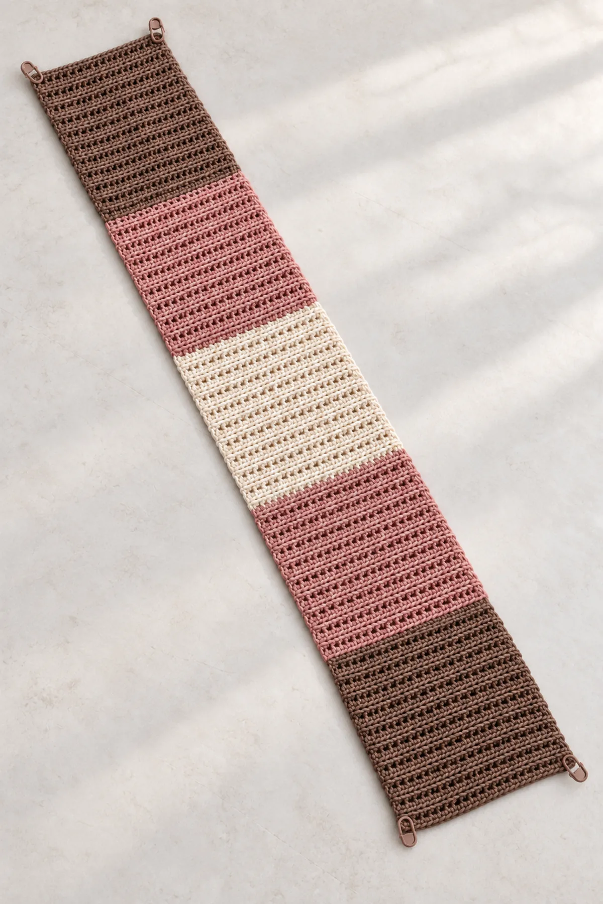 Unseamed five-block cocoa, rose and cream crochet rectangle laid flat before folding the sleeve ends.