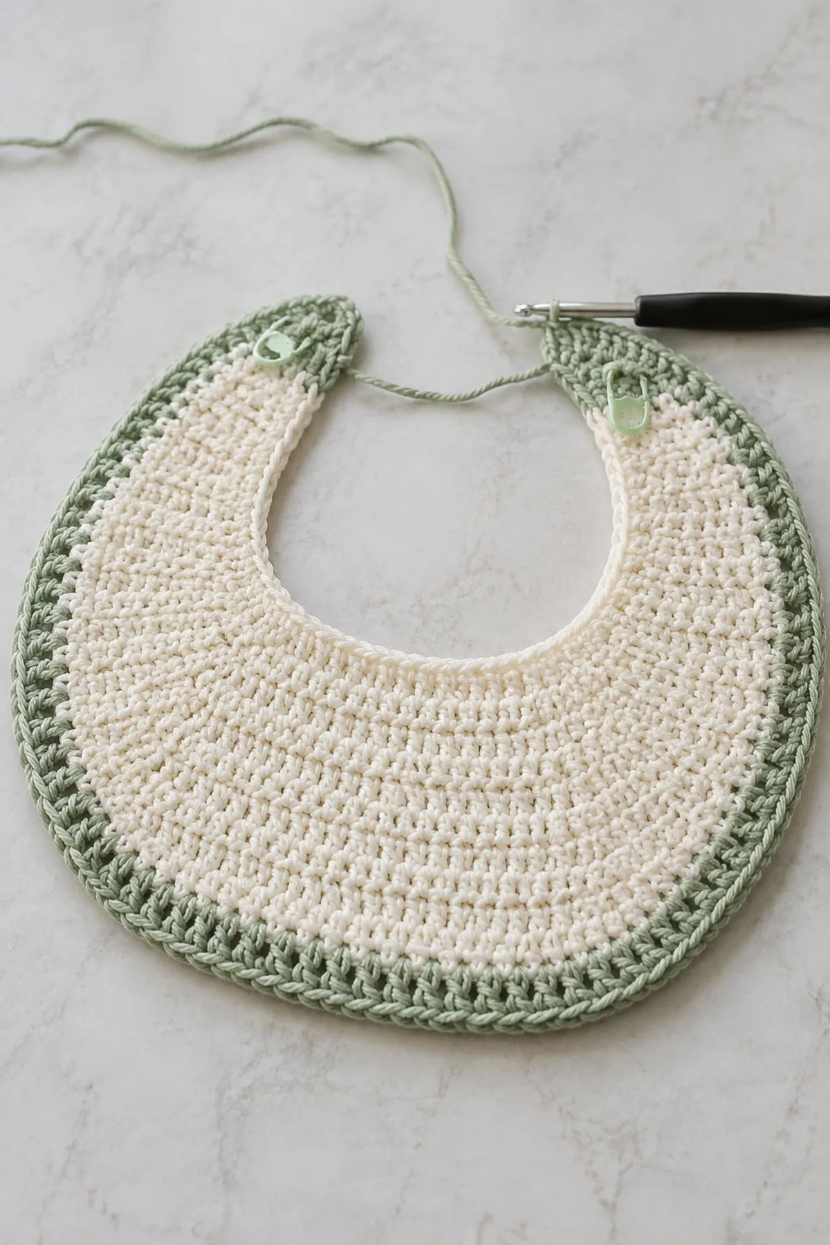 Early counted crochet stage of easy crochet baby bib with matching yarn and hook
