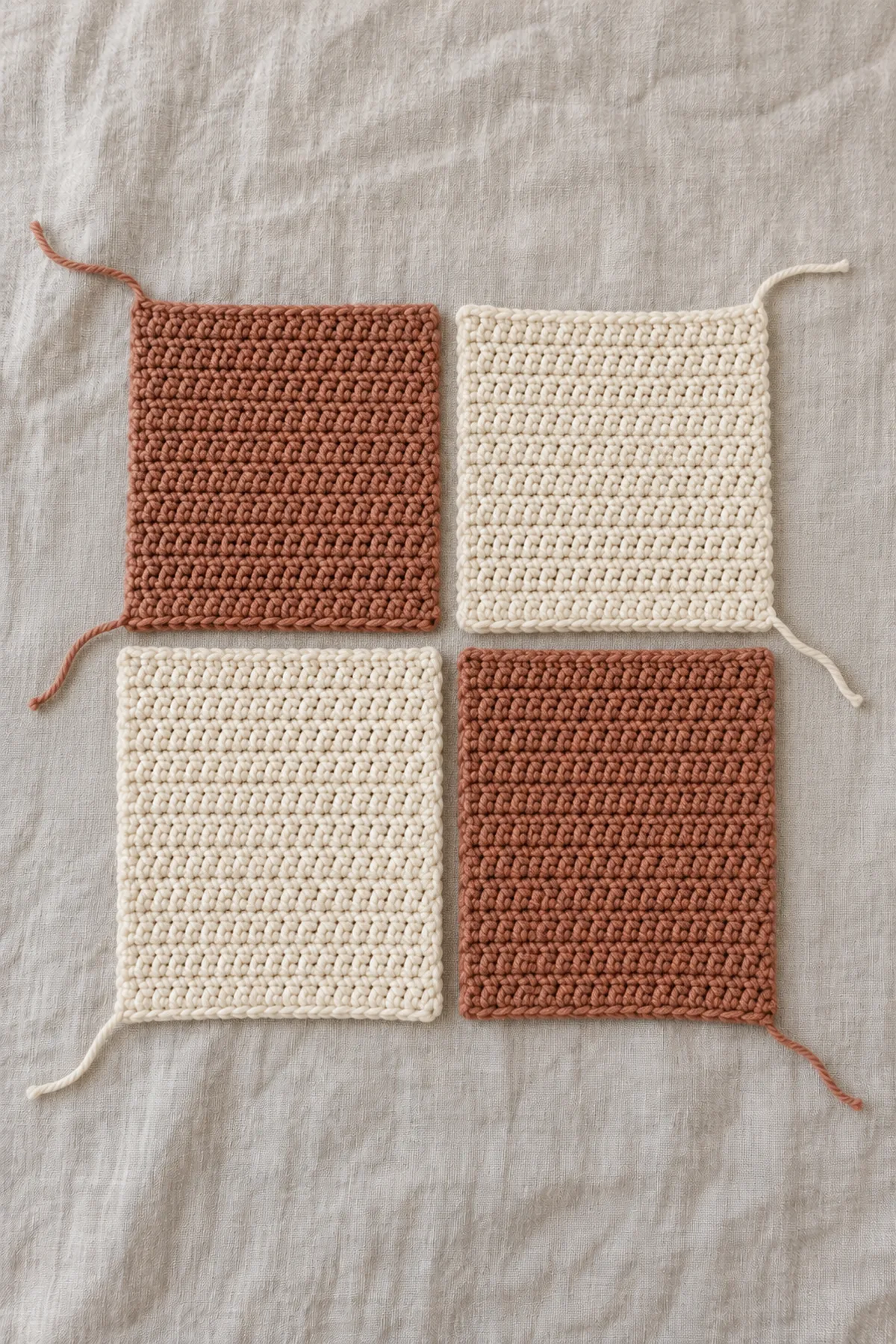 Four separate solid cream and clay rectangles arranged as an asymmetric two-by-two cardigan back map on a work surface.