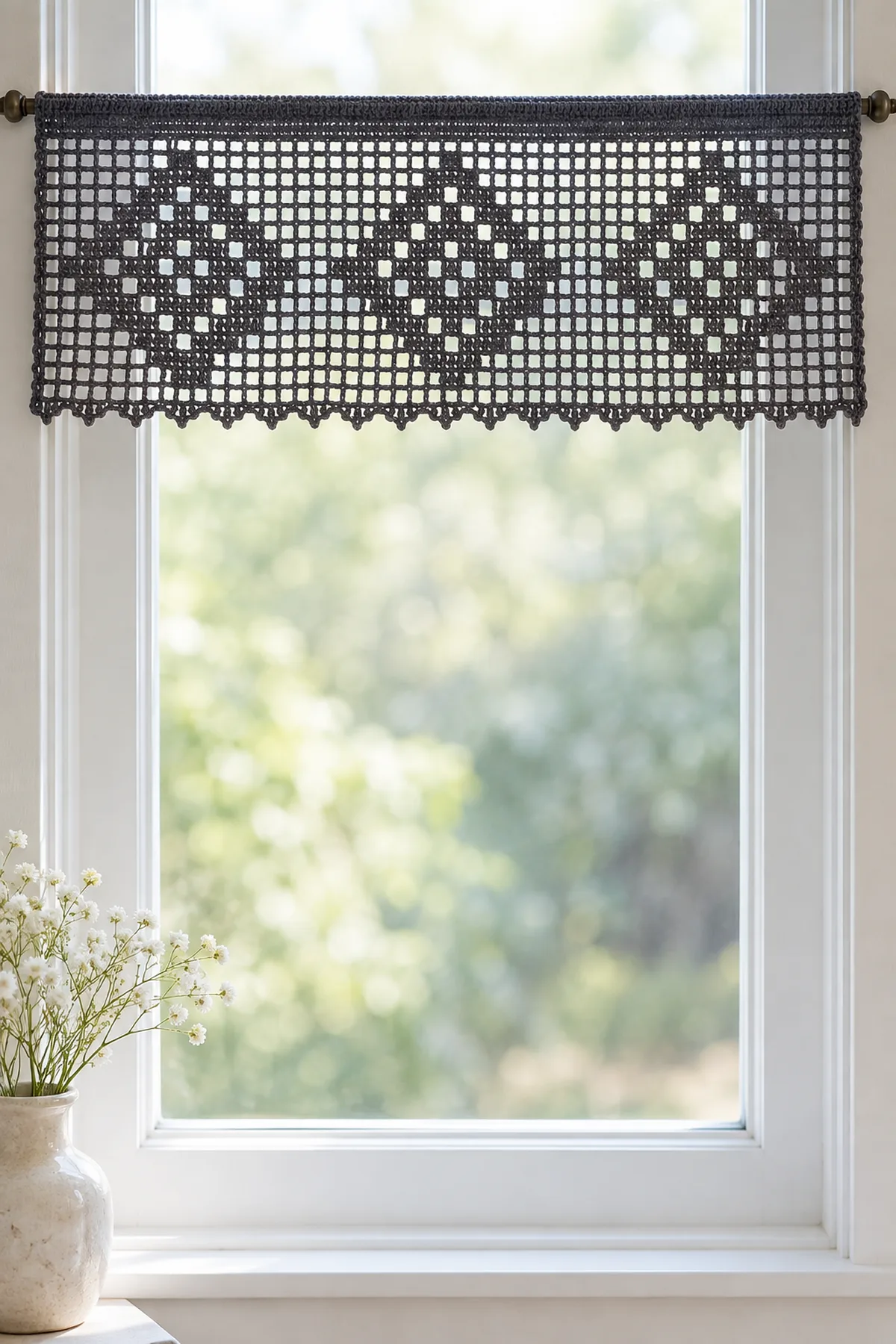 Original charcoal fine-cotton crochet window valance, one long shallow rectangular open filet mesh panel with THREE geometric stepped diamond web motifs across it, solid folded rod channel at top, tiny pointed picot lower edge. About 22.5 inches wide by 8.5 inches drop. Hanging straight from a slim rod against a bright plain narrow window. Not round doilies, no fringe, no spiders or cords