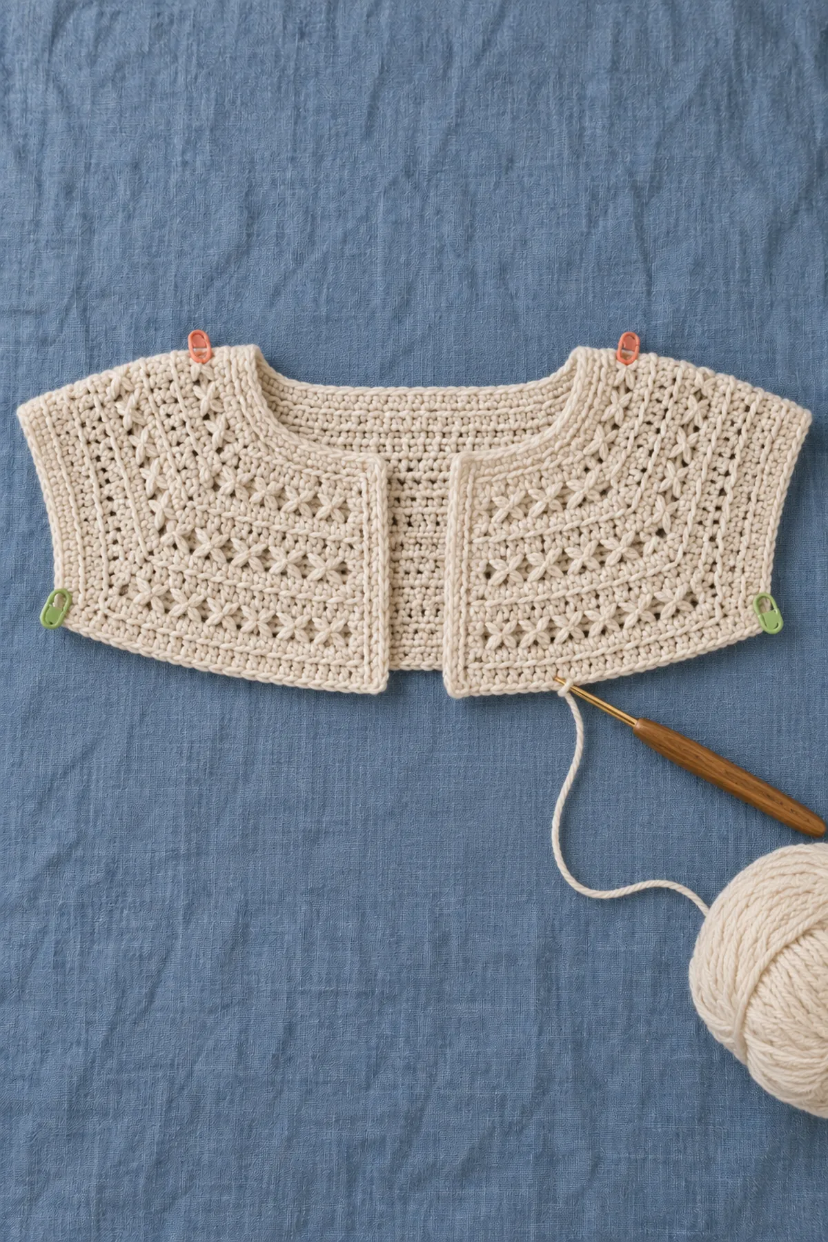 Unfinished warm ivory rectangular crochet yoke with four marked corners and compact crossed-stitch bands separated by solid shaping rows
