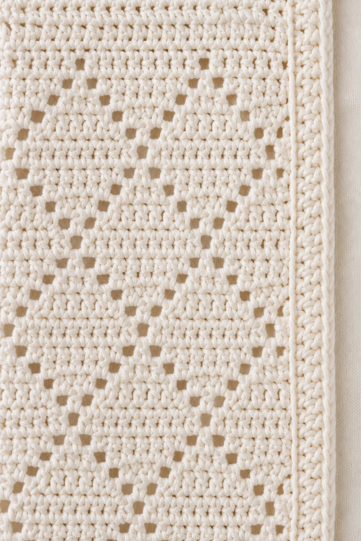 Macro of very small one-chain filet diamond windows in fine ivory cotton, solid filled cells and firm seam anchors, no large mesh