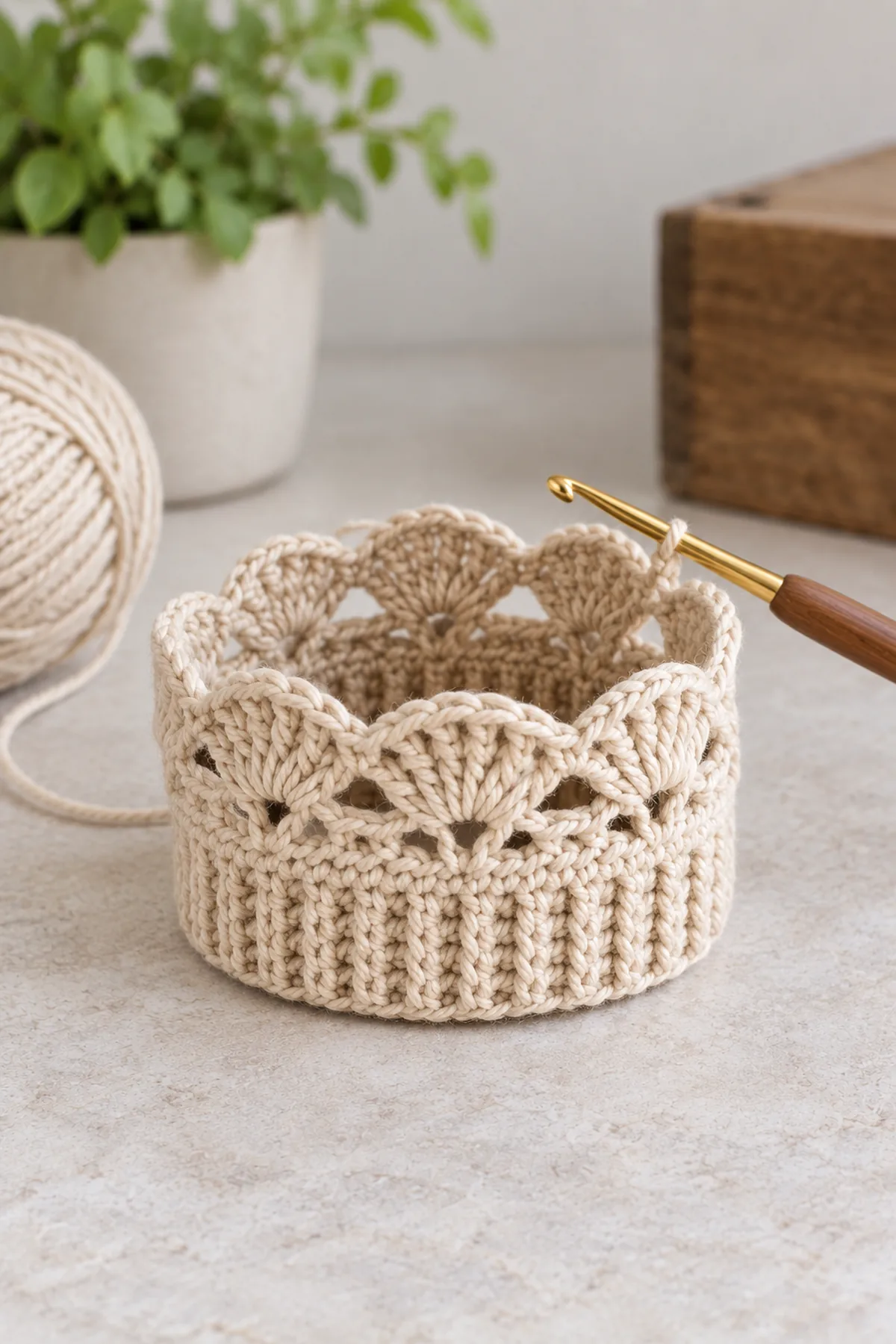 One oat crochet boot cuff band joined into a short tube with upper base and first row of fourteen small five-dc fans; next rounds not yet made, no elastic yet, hook at live lace edge; hollow tube clearly visible.
