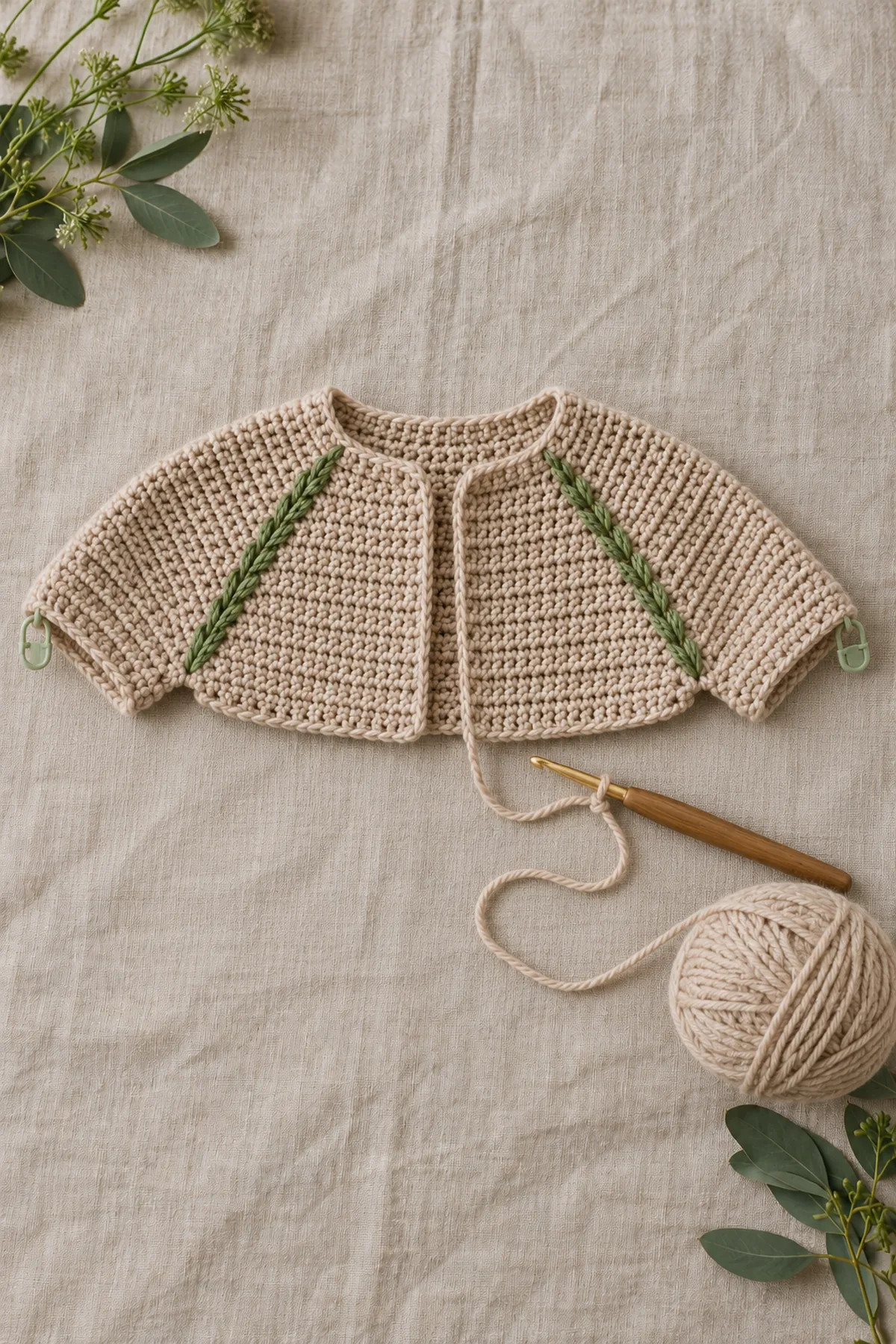 Top-down crochet raglan baby cardigan yoke with four paired raised green seam tracks and marked sleeve sections before separation