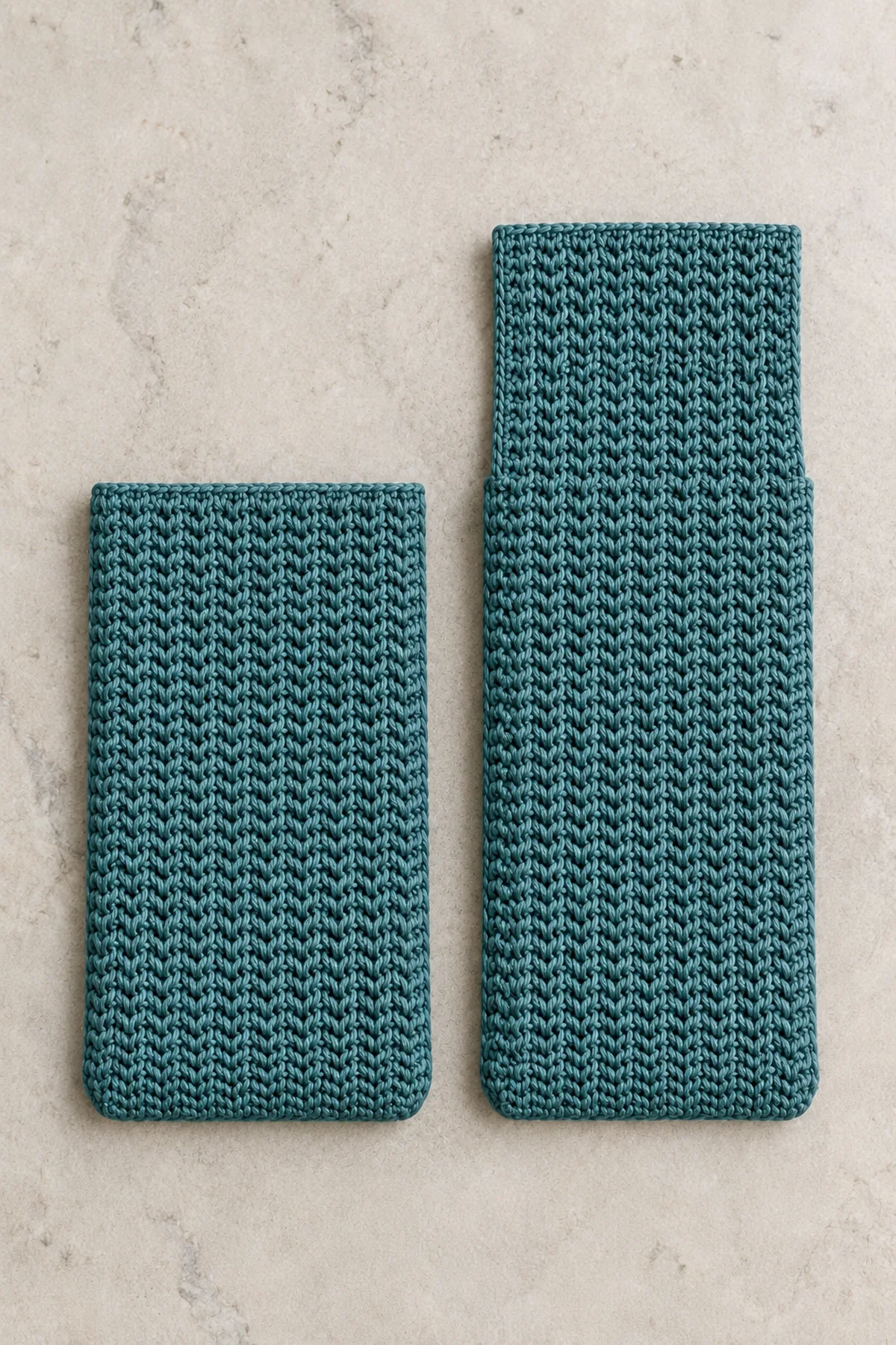 Two separate teal herringbone crochet rectangles on pale stone table: one short phone-pocket front, one same-width back extending about one third taller into a straight rectangular flap. Width about 4.4 inches, front height 7.6 inches, back height 10 inches. No strap, no seams, no boxed corners yet