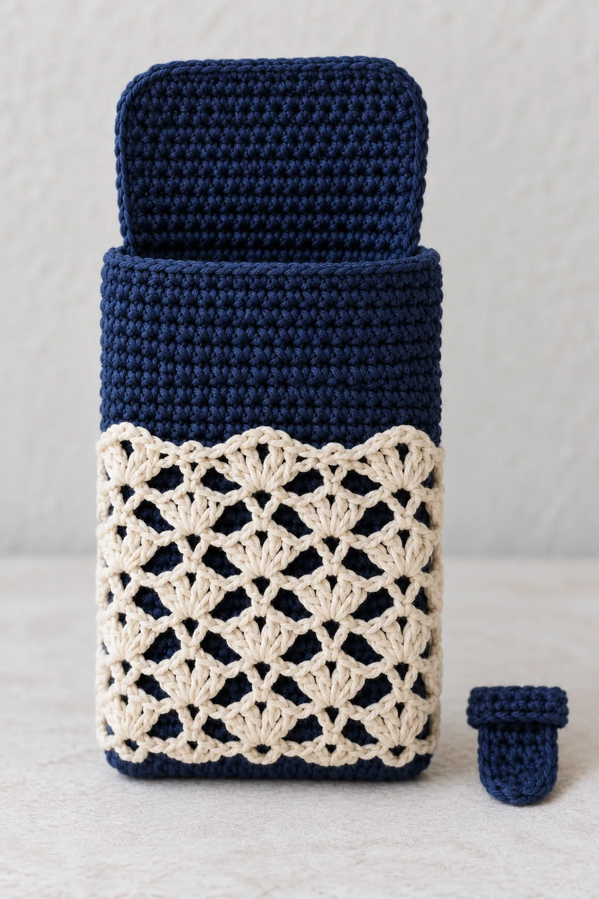 Navy crochet phone pocket body with separate cream openwork rectangular lace overlay aligned to front and an unattached small navy keeper strip, flap open