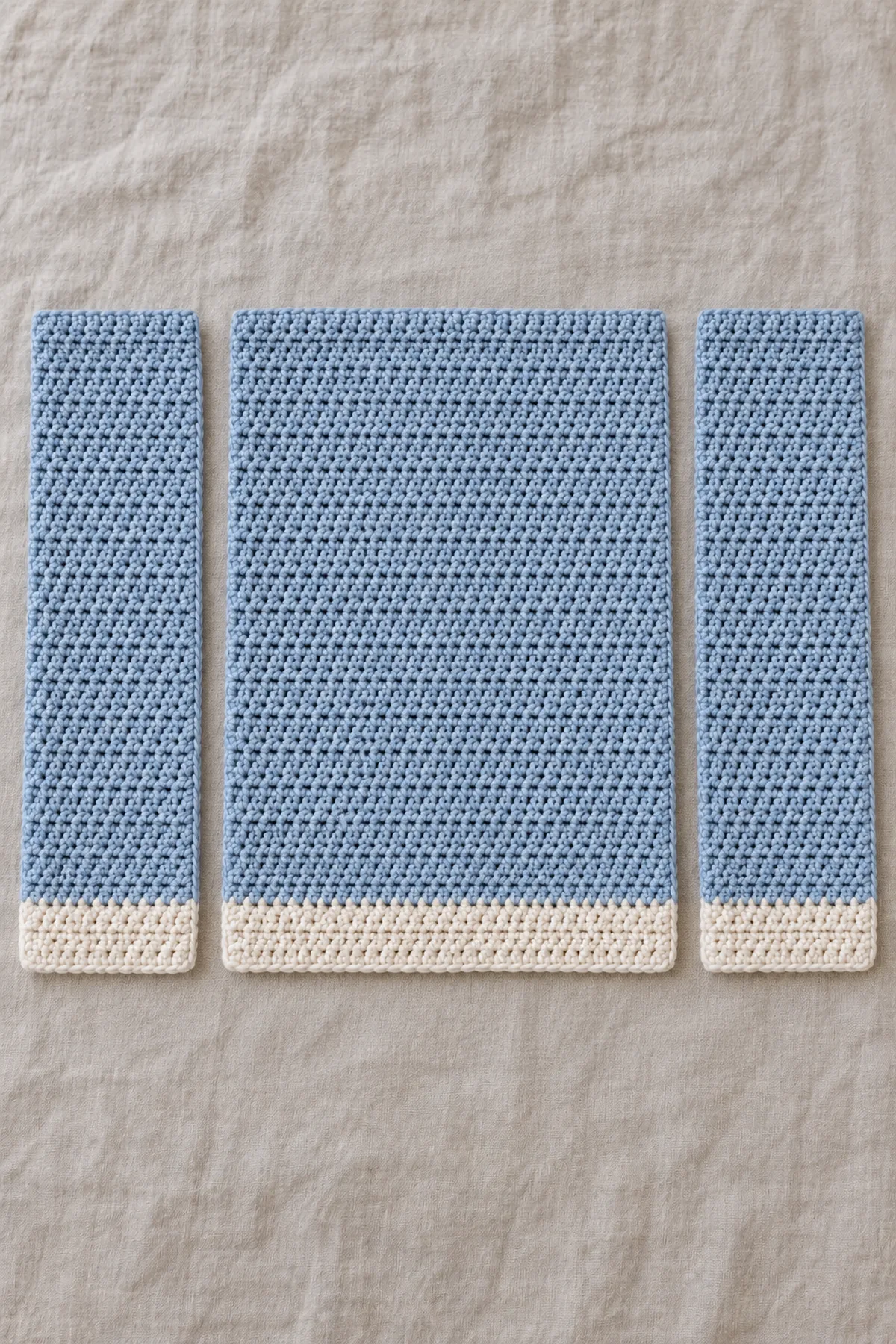 Three separate straight blue-and-ecru hdc rectangles: one wider back and two equal narrower fronts, aligned ecru four-row hems, square top corners and perfectly straight sides; no cut-out armholes or sleeves.
