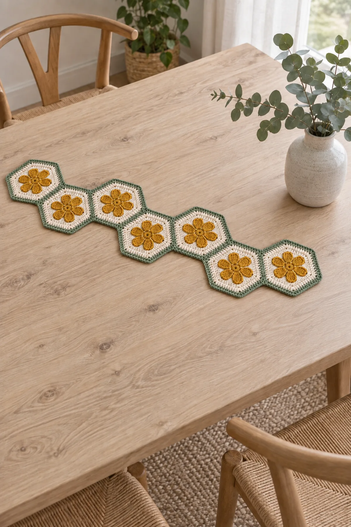 Same narrow runner with EXACTLY seven cream hexagons and flat mustard six-petal daisies in one long alternating zigzag chain, fine sage seams and border, pale dining table with empty cool vase beside rather than covering runner, entire seven flowers visible, no candle or hot cookware