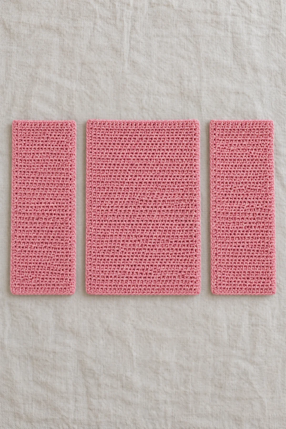 Three separate perfectly rectangular rose-pink single-crochet body panels, one wider back and two equal fronts with straight sides and square corners; no shaped armholes, sleeves or petals.
