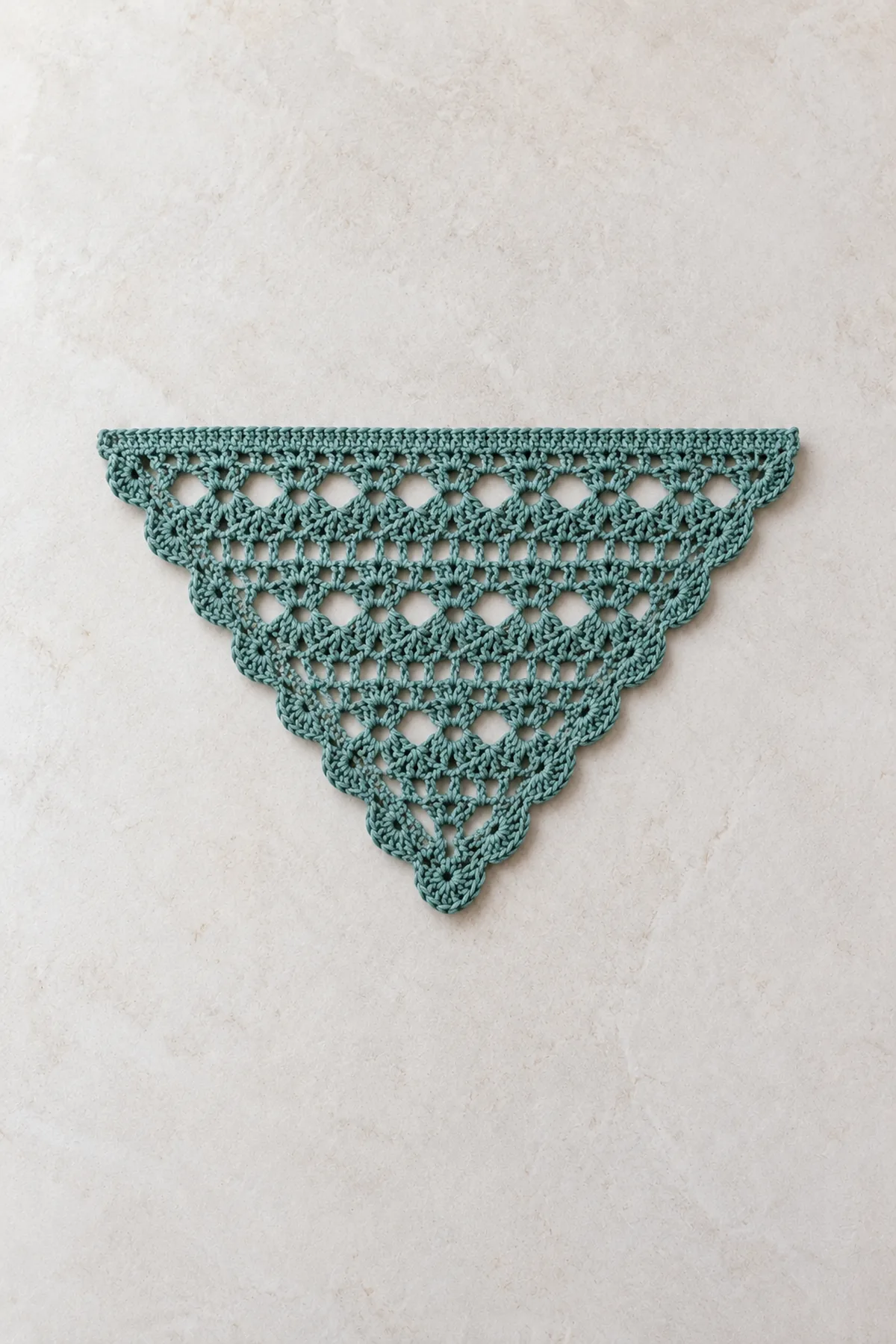 Partially grown muted-teal shallow crochet triangle with clear alternating V-stitch and eyelet rows, top edge not full width, no border or ties
