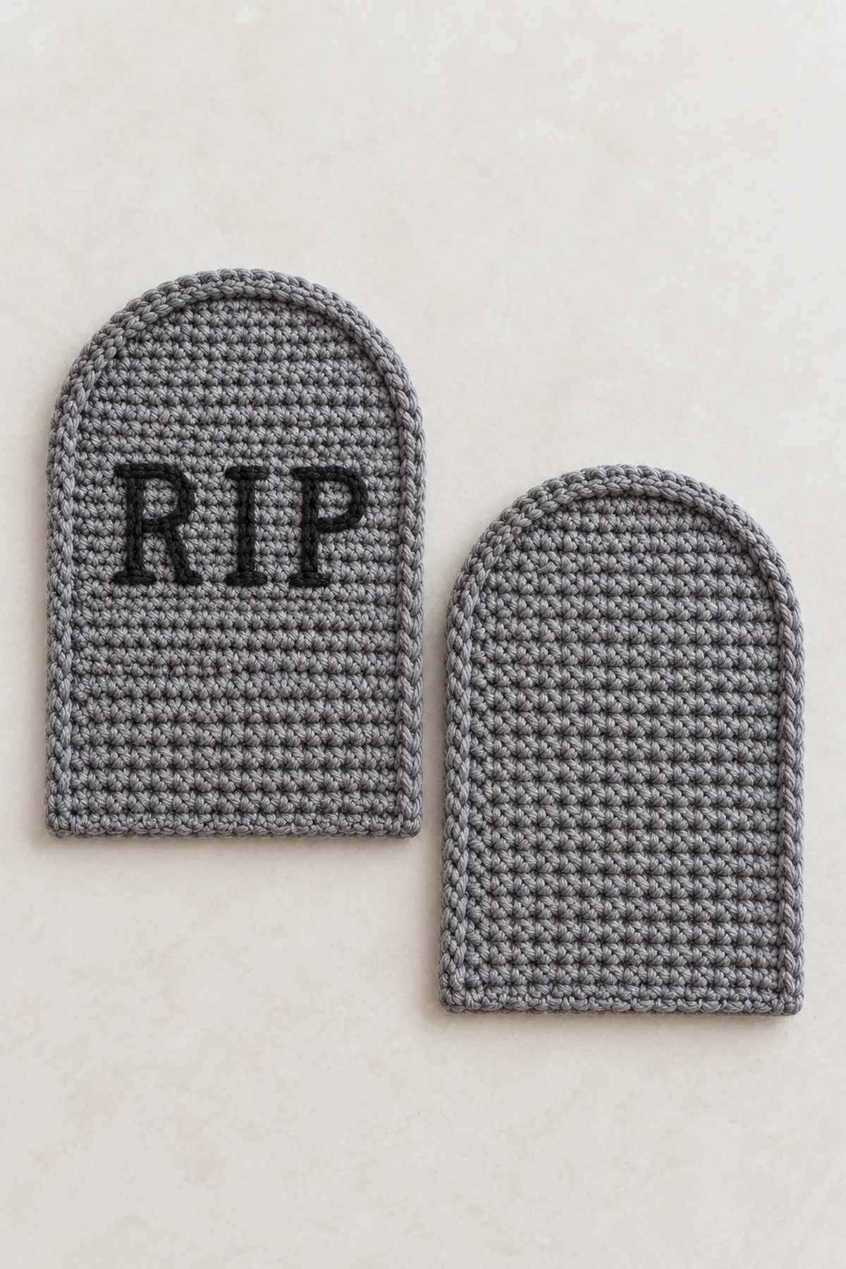 Two matching flat slate gray crocheted tombstone face panels laid separately, each with straight lower sides and shaped rounded arch top, one has small embroidered RIP letters