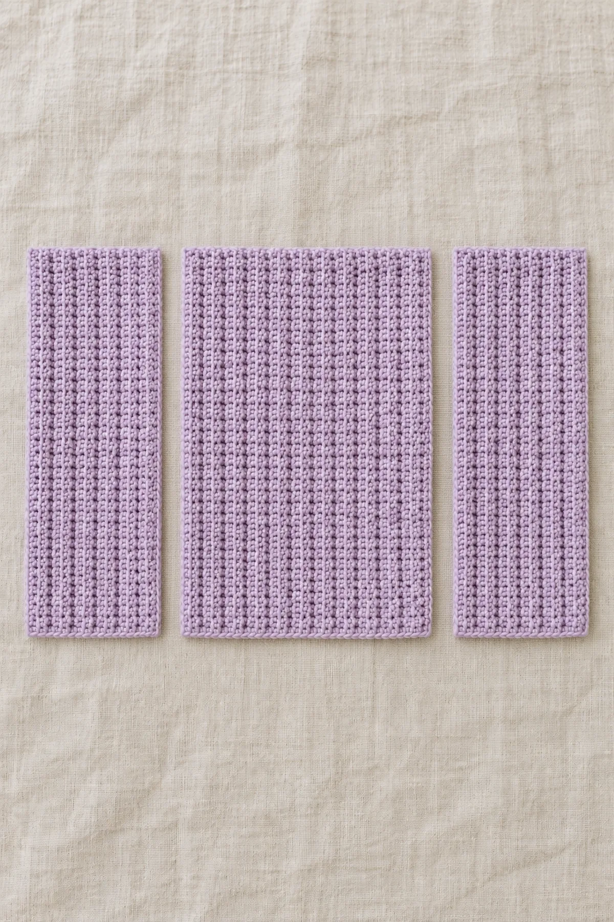 Three separate sideways crocheted lilac back-loop single crochet panels laid flat: one wider back and two narrower equal fronts; vertical ridges clear, no sleeves or seams.