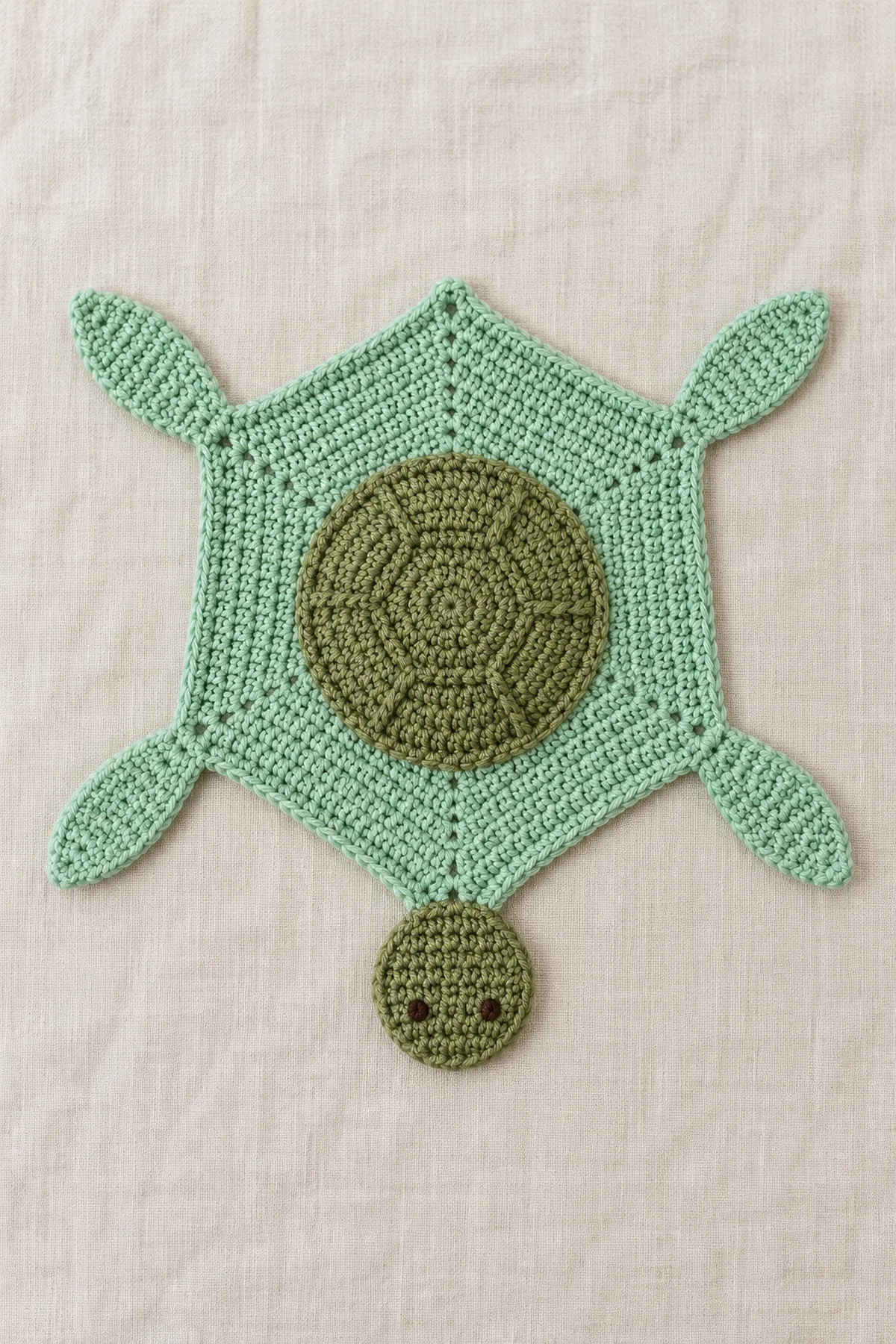 Original mint crochet hexagonal turtle lovey spread fully flat on cream linen, six clearly defined corners, shallow olive domed center shell, one flat olive head projecting from one vertex and four flat tapered mint flippers at side vertices, embroidered tiny eyes only.