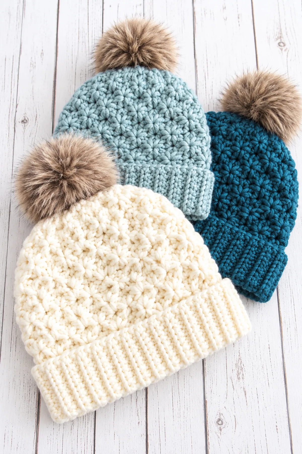 Finished cream Jenna crochet beanie with wide ribbed brim, compact star-cluster texture and soft taupe pompom beside mist-blue and deep-teal versions; no text.