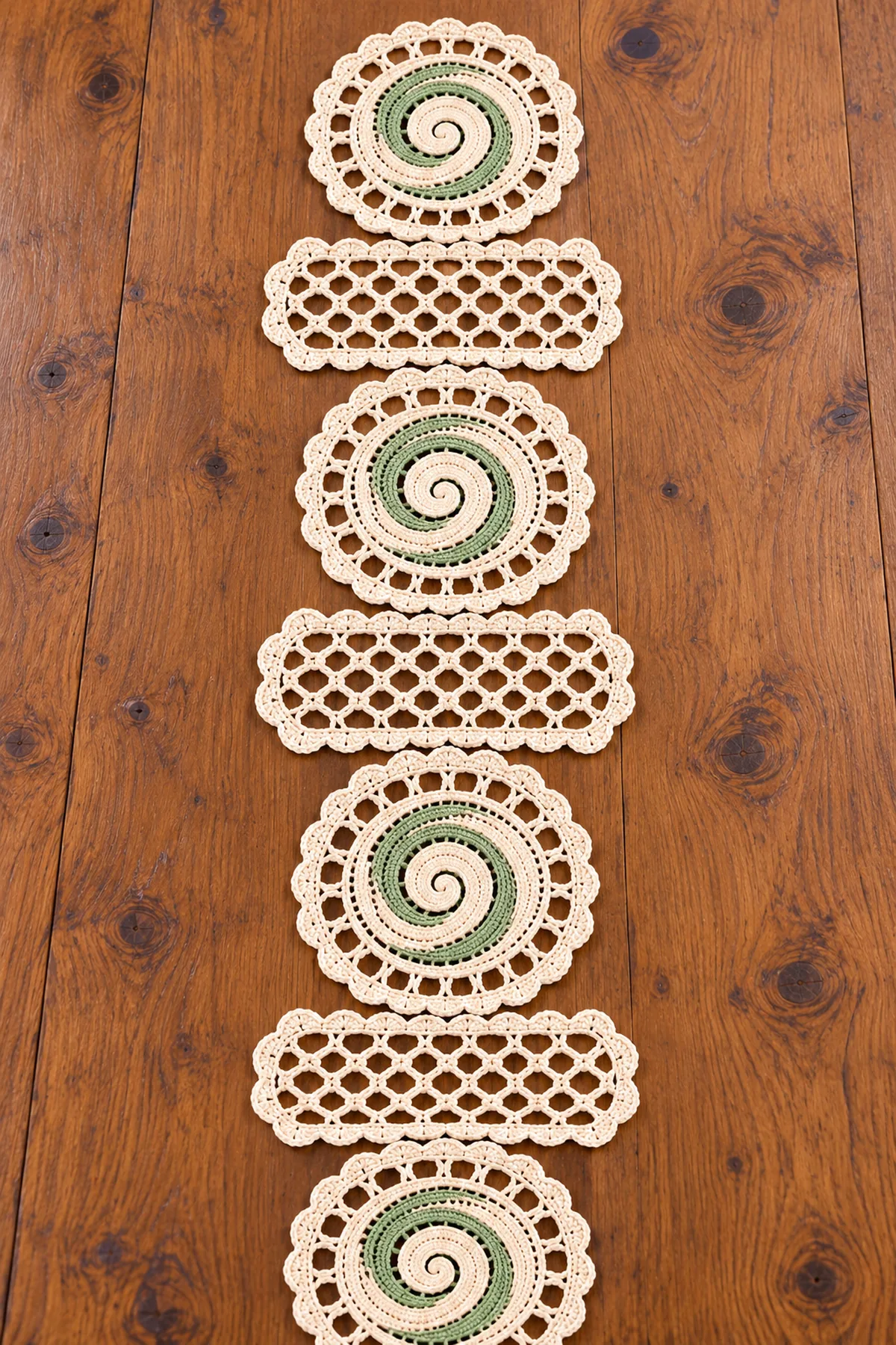 Four cream spiral medallions and three rectangular open-mesh lace panels laid out in sequence before joining, with counted crochet edges visible